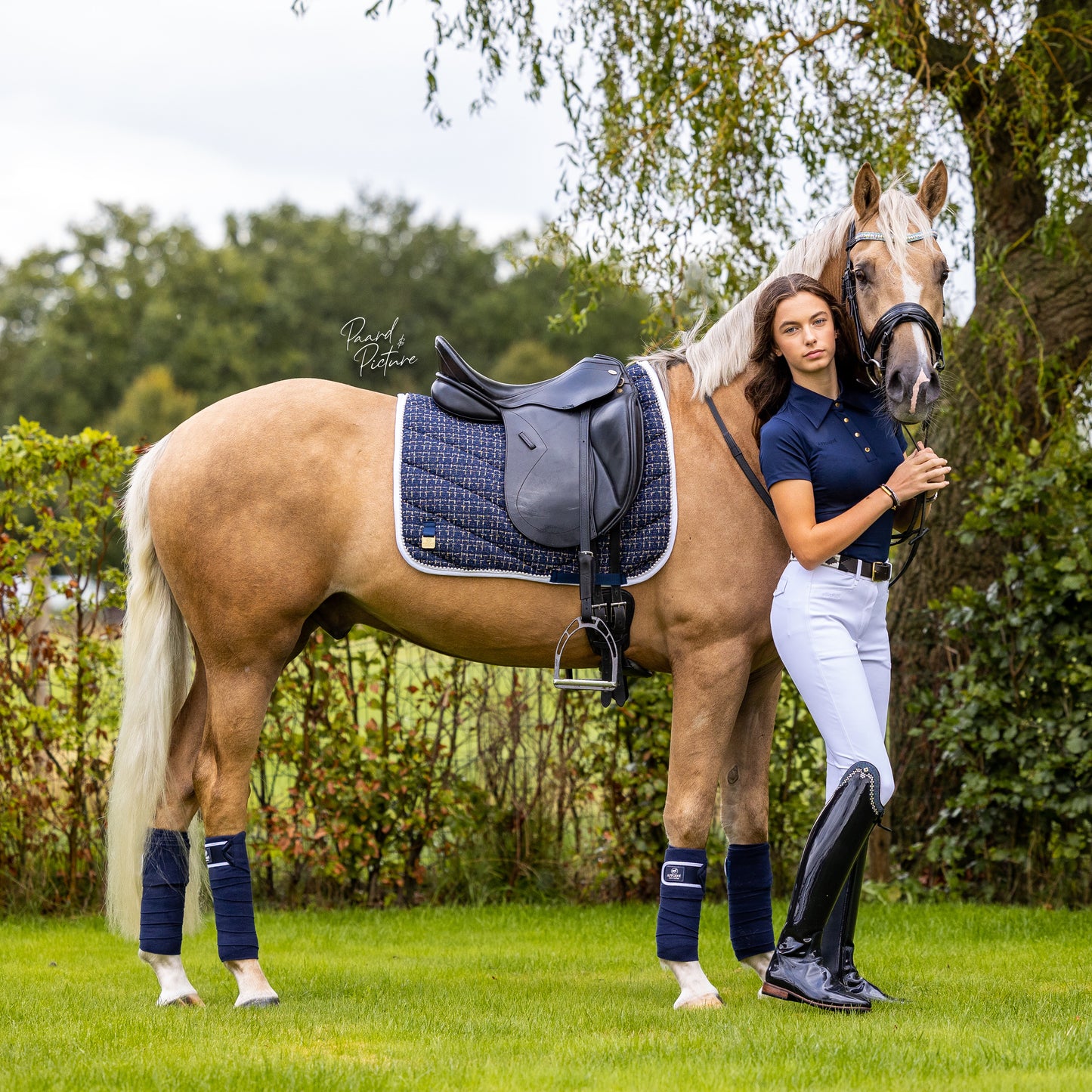 Djaydee van den Berg in ons navy blauw dressursjabrack zadeldekje met parels en blauwe bandages.